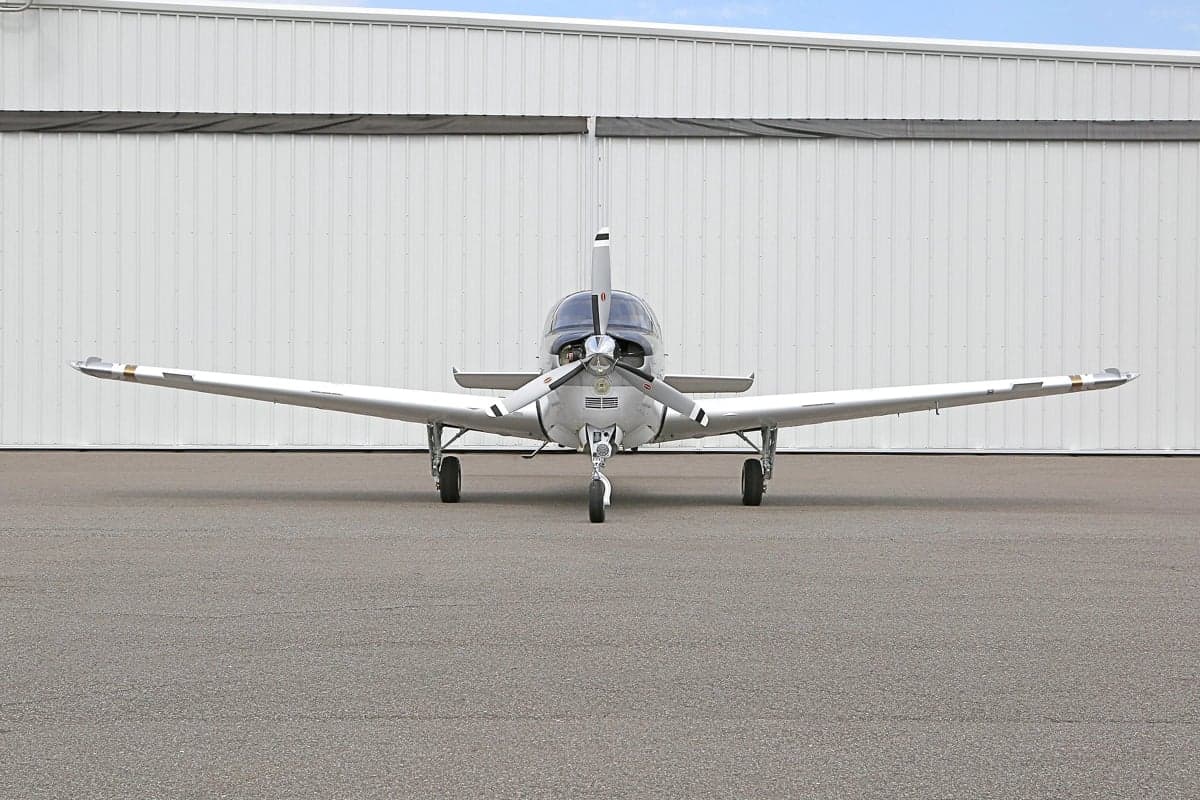 Front view of a white and silver Beechcraft Bonanza on the tarmac.