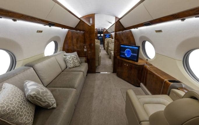 Aircraft cabin interior with a sofa and a single seat.
