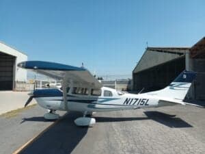 A Cessna aircraft with blue and white paint scheme, parked on the tarmac with the tail number N1715L visible.