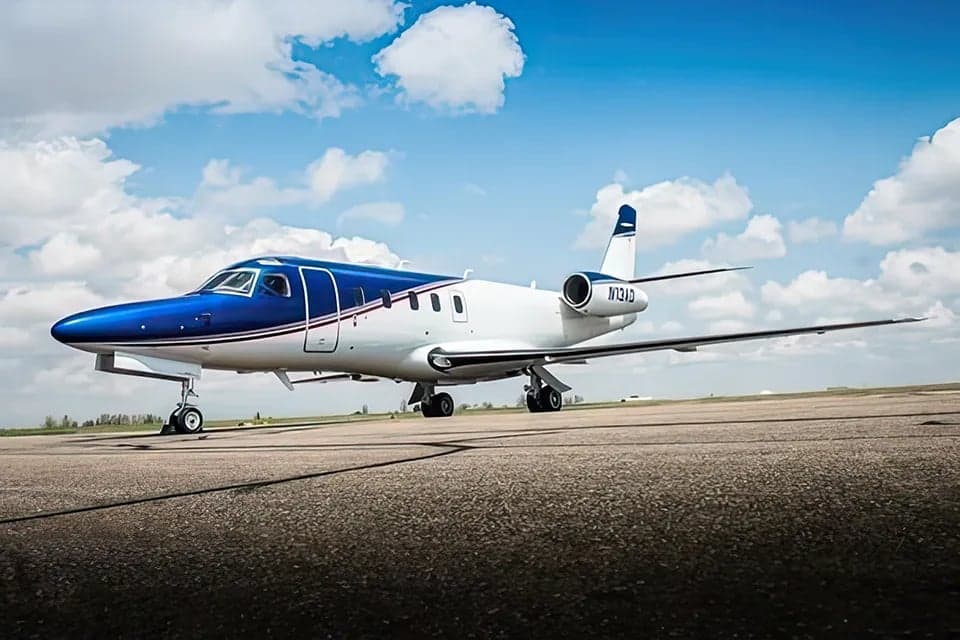 A Cessna Citation CJ3 is parked on the tarmac with a blue and white paint scheme.