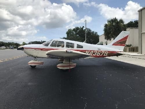 A Piper PA-28-181 Archer II aircraft with a white and red paint scheme parked on the tarmac.
