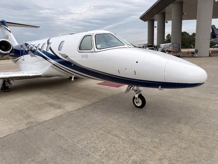 A close-up view of the nose of a white and blue Cessna Citation CJ4 business jet on an airport tarmac.