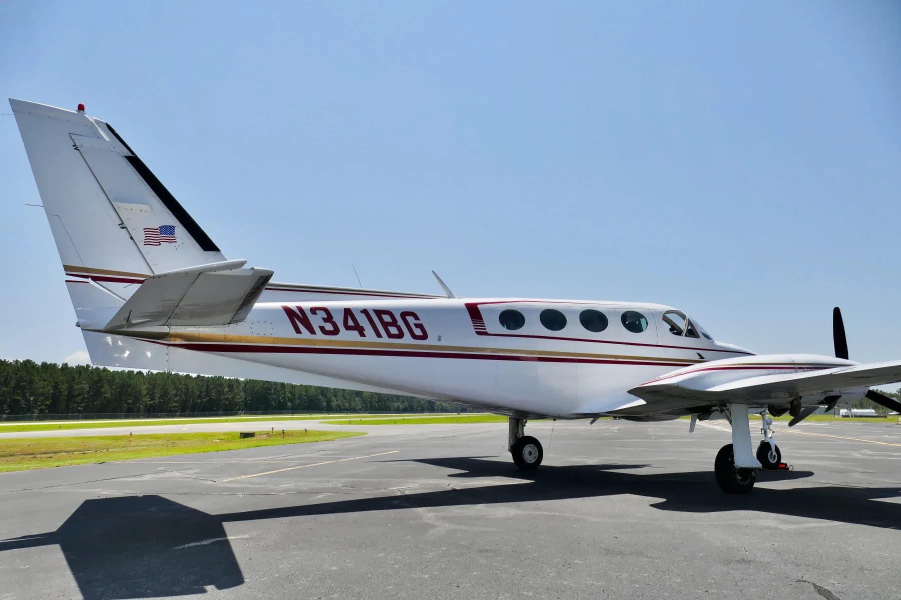 Side view of the rear fuselage and tail of a white twin-engine propeller aircraft N341BG.