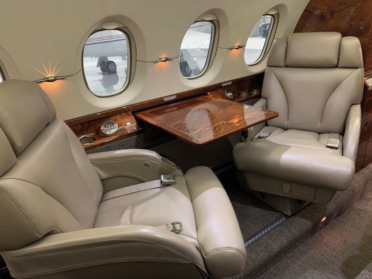 Aircraft cabin with leather seats and a table.