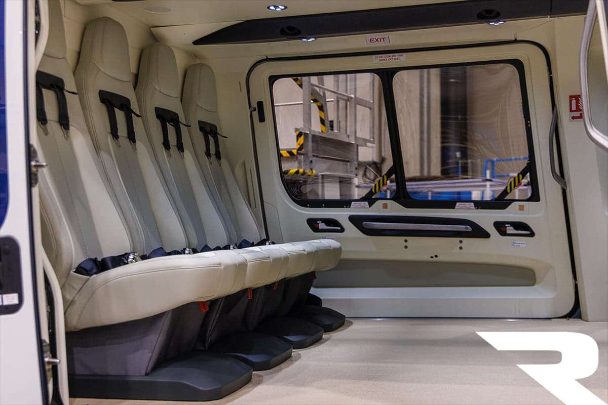 The interior cabin of an Airbus H160 helicopter showing a row of passenger seats and a large side window.