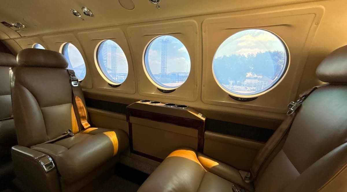 Interior of a King Air 250 with leather seats and round windows.