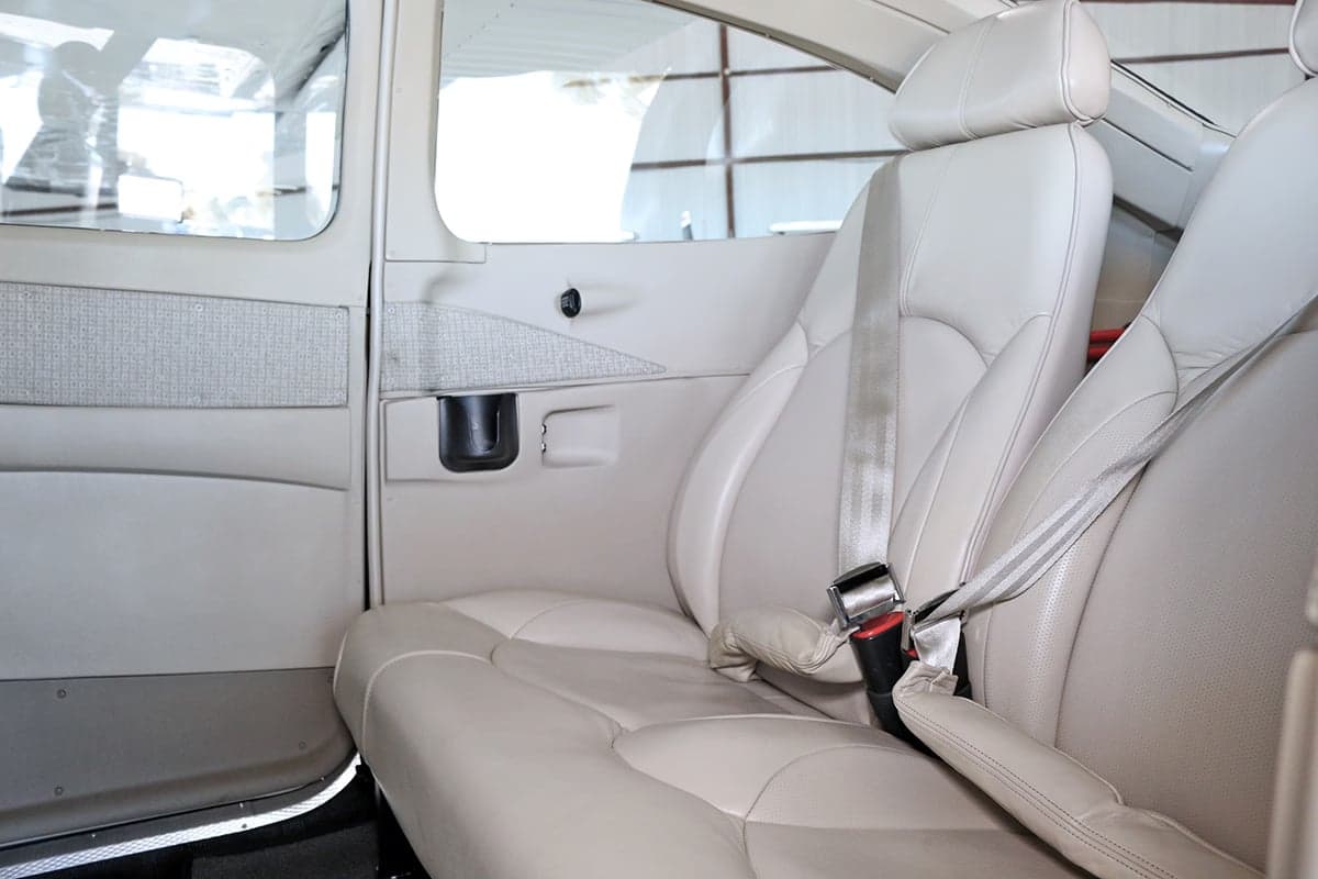 The interior of an aircraft cabin with cream-colored leather seats.