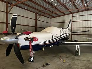 Turboprop aircraft with registration N2424X parked in a hangar with a cover on part of the fuselage.