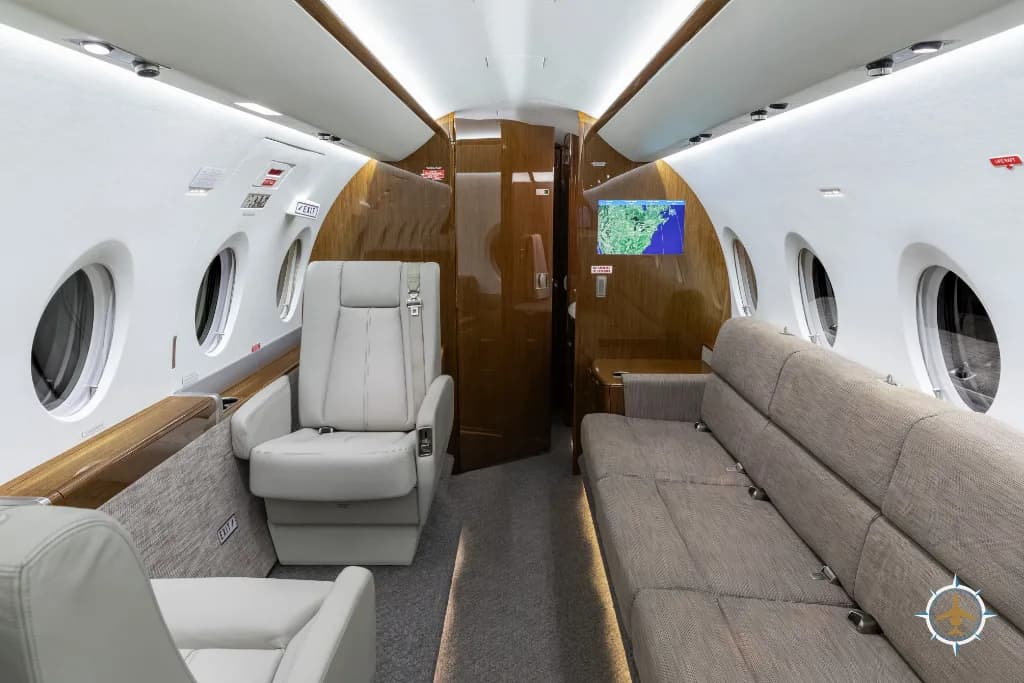 A view of the aircraft cabin showing a long grey sofa and a single light grey leather seat.