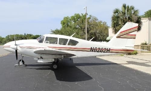 A Piper PA-28-181 Archer II with a white and brown stripe paint scheme is parked on the tarmac.