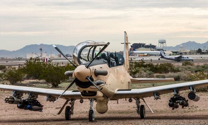 An AT-6 light attack aircraft parked on the tarmac at an airport.