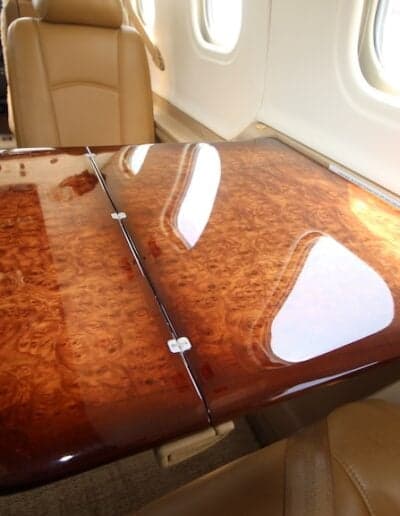 View of the aircraft's interior with a wooden table and leather seats.