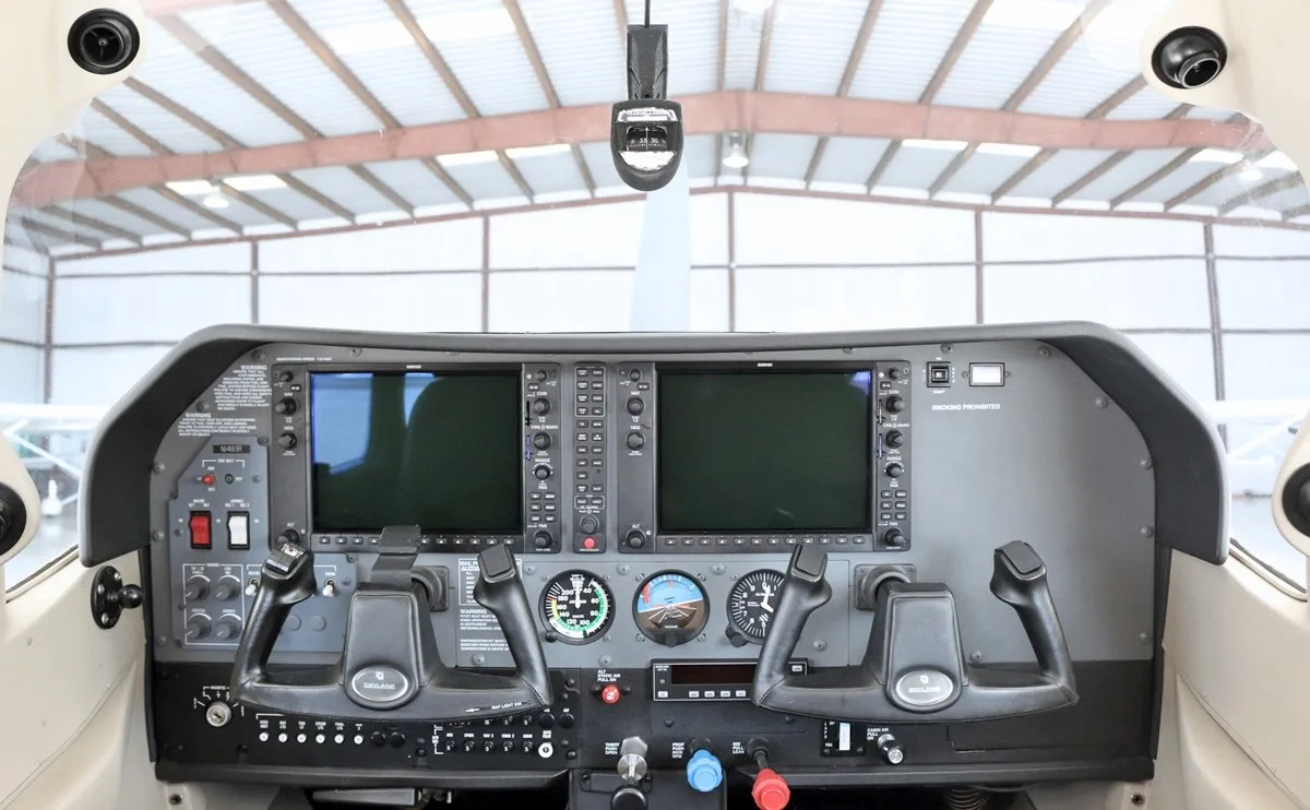 The cockpit of a Cessna Skylane, featuring a modern glass panel with two large display screens and dual control yokes.