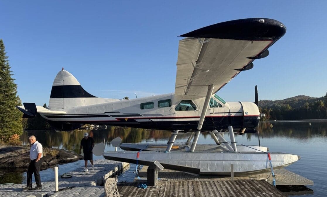 A de Havilland Canada DHC-3 Otter floatplane is docked on a lake.