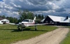 A small aircraft parked on a grassy area in front of a building.