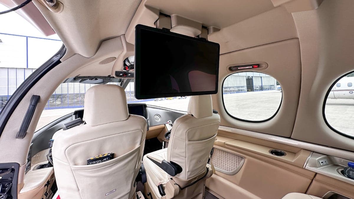 The interior of the Cirrus Vision Jet features a monitor and cream-colored leather seats.