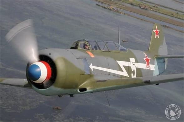 A Lavochkin La-9 in flight with a gray and green paint scheme and a red star on the tail.