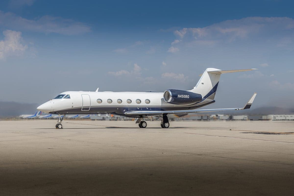 Side view of a white and blue Gulfstream G450 on the tarmac.