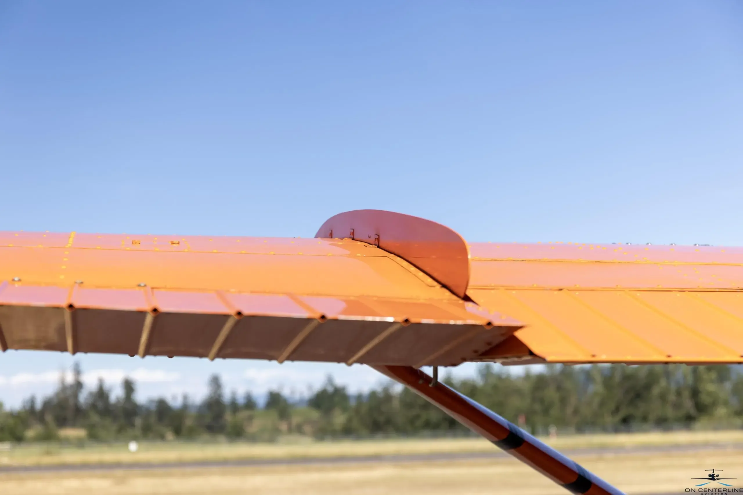 Close-up of the wing of the orange and white Cessna 182 Skylane RG.
