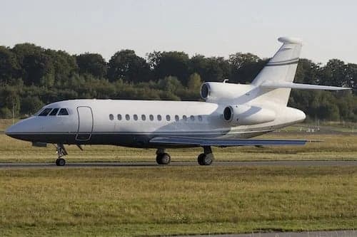 A white Falcon jet sits on the tarmac.