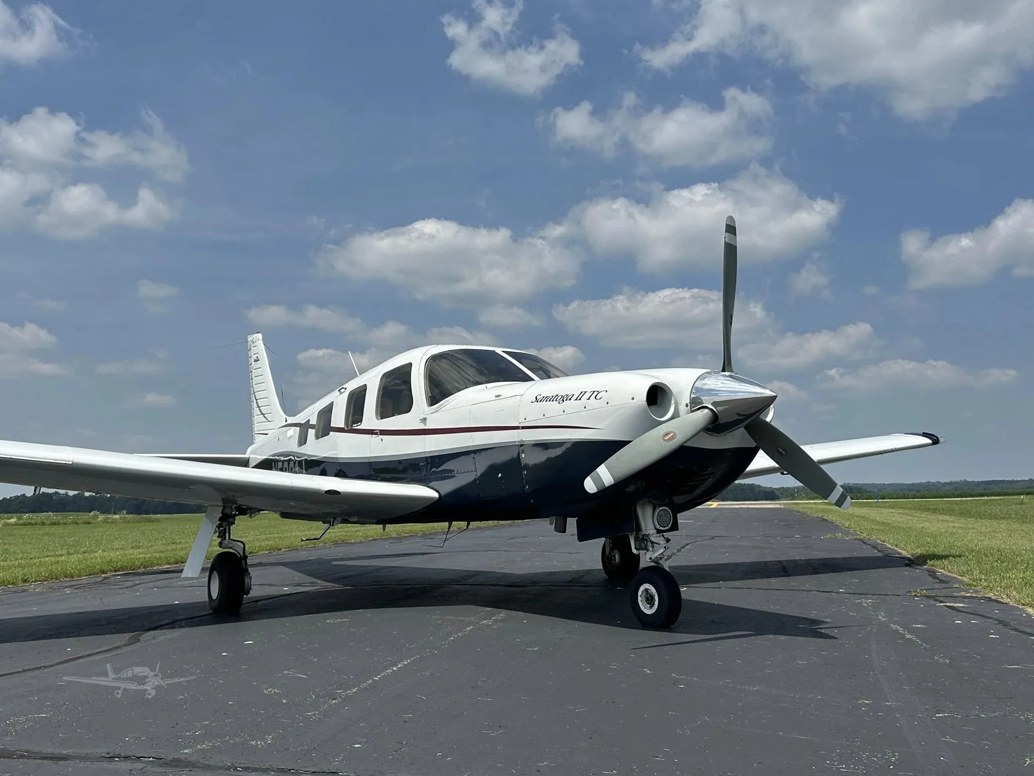 A front-quarter view of a white and blue Piper Saratoga II TC (N5361J) parked on an airfield.