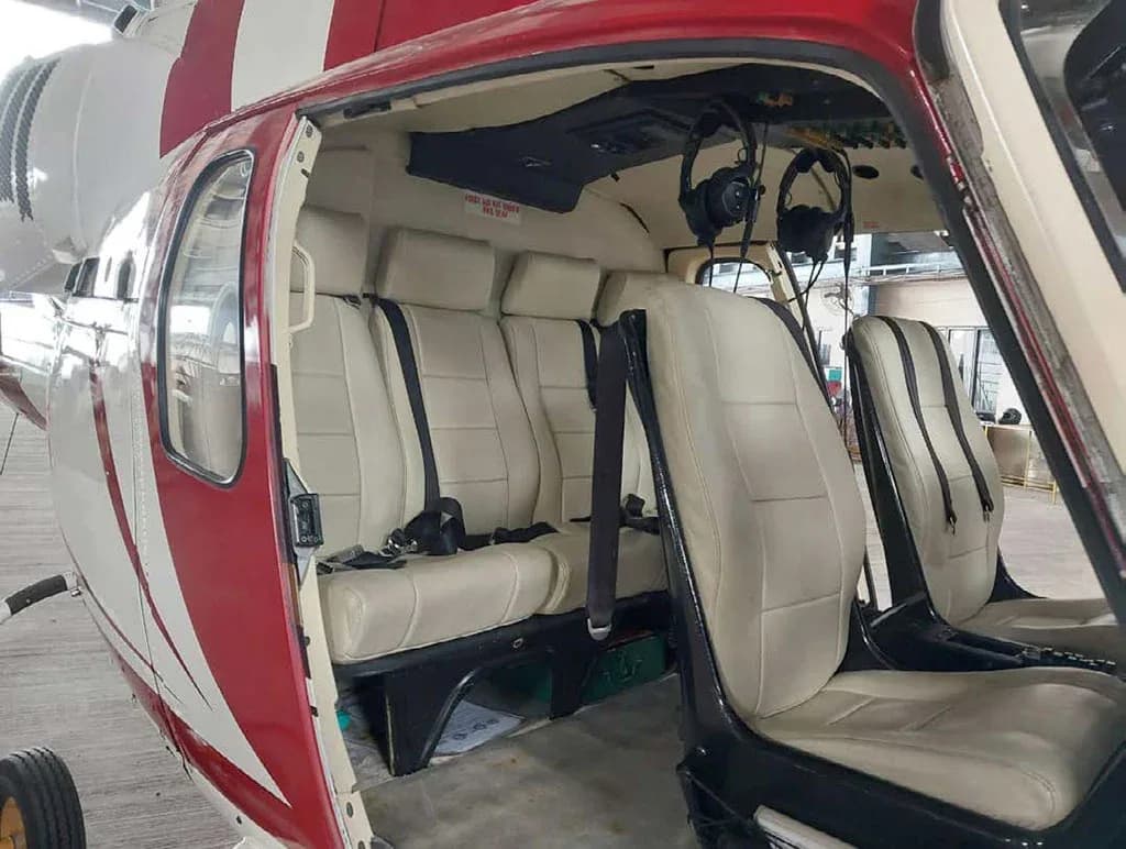 The open door of the helicopter revealing the light beige interior seats and part of the red and white exterior.