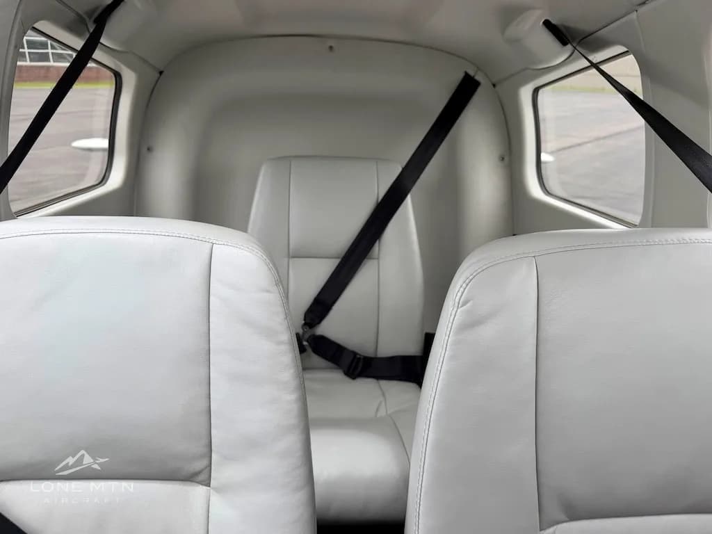 A view of the light gray rear cabin seat with a black seatbelt, seen from between the front seats.