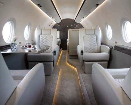 Luxurious private jet interior with white leather seats and a small table.