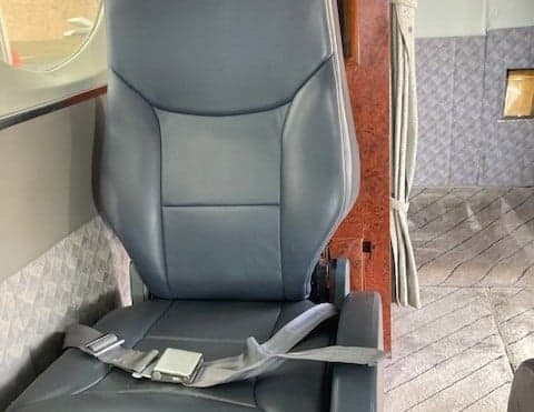 Close-up of a gray leather seat with a seatbelt in the aircraft cabin.
