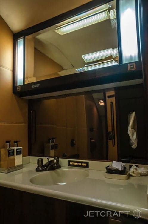 Aircraft lavatory with sink and mirror.