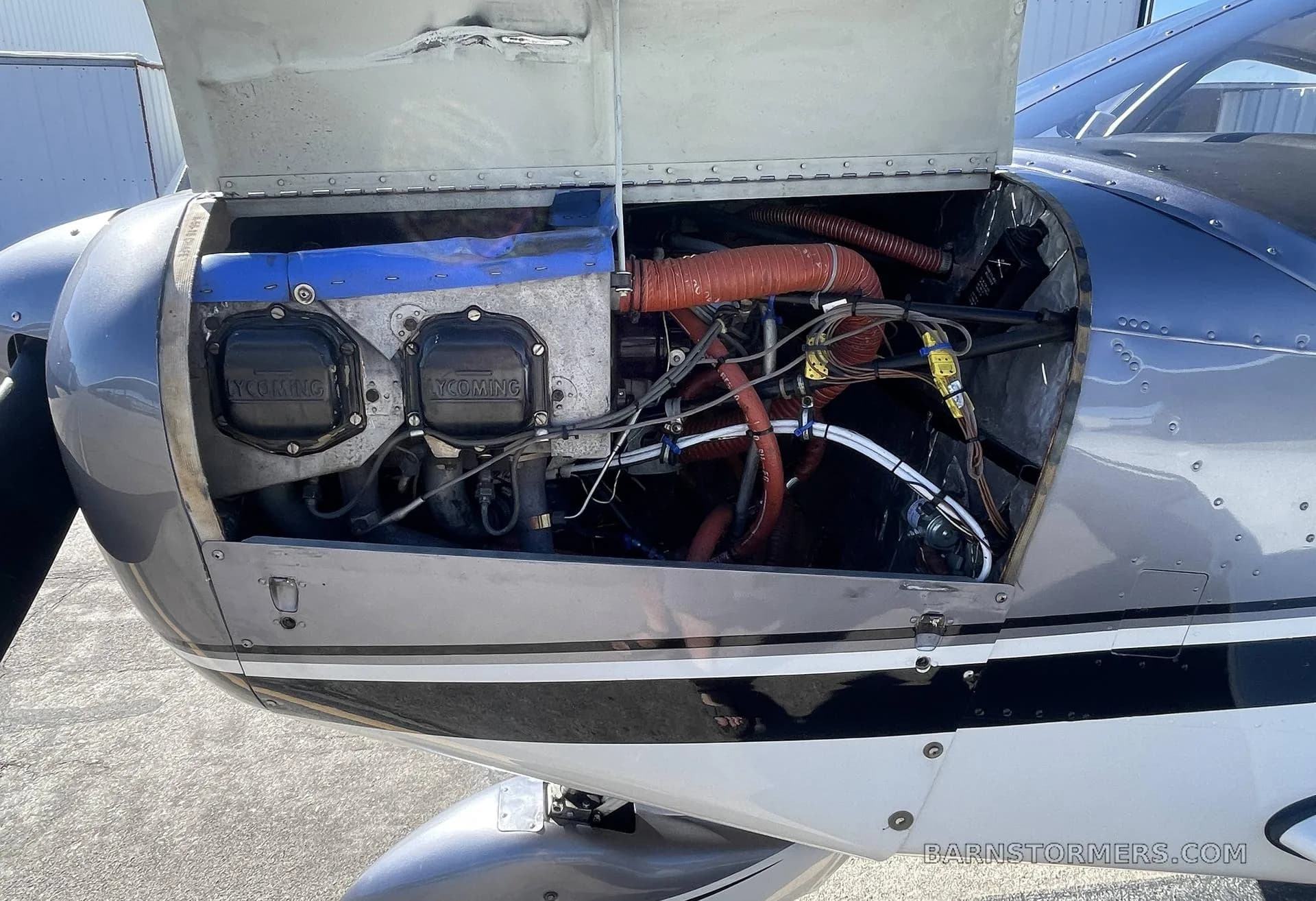 A close-up view of the Lycoming engine compartment of a Piper Cherokee 140 with the cowling open.