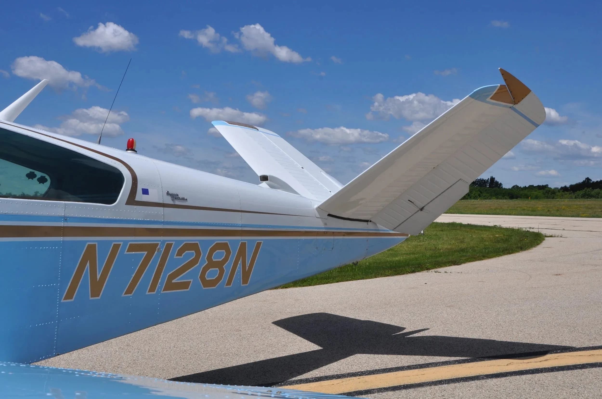 A close-up view of the tail section of the light blue and white Beechcraft Bonanza N7128N.
