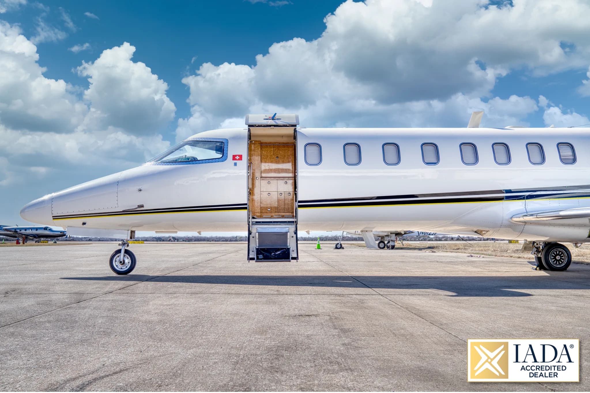 A close-up side view of the front section of a white Learjet 60 (N275ER) with its main cabin door open, revealing the steps.