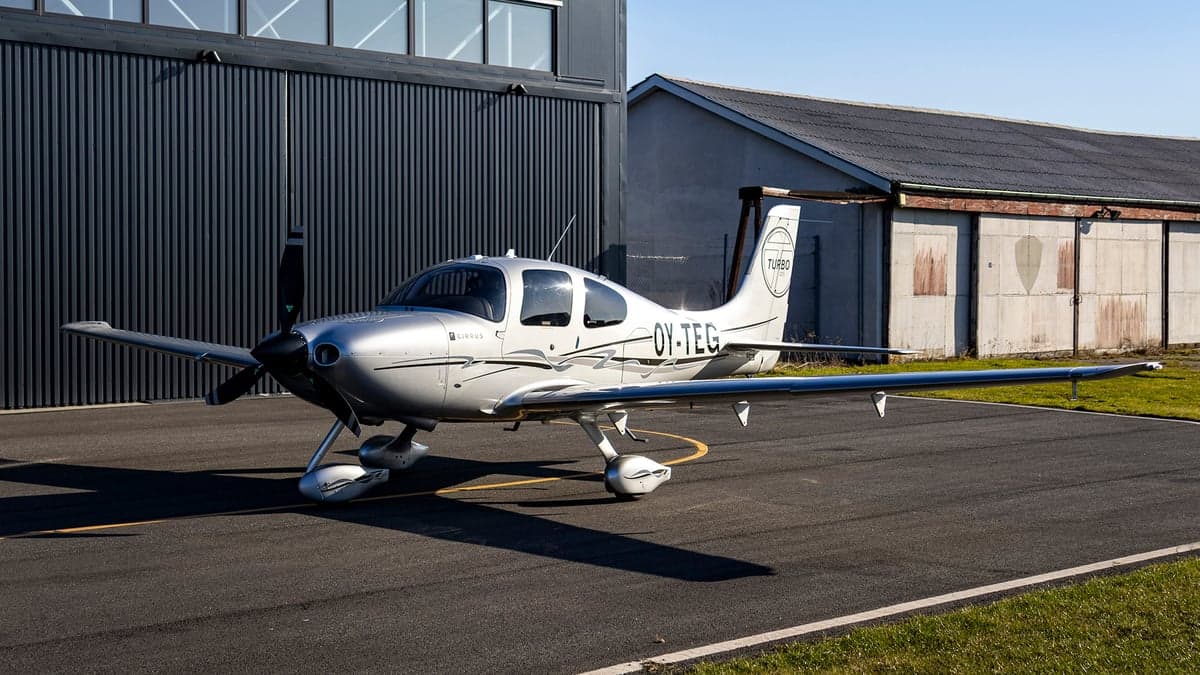 Side view of the silver Cirrus OY-TEG on the tarmac.