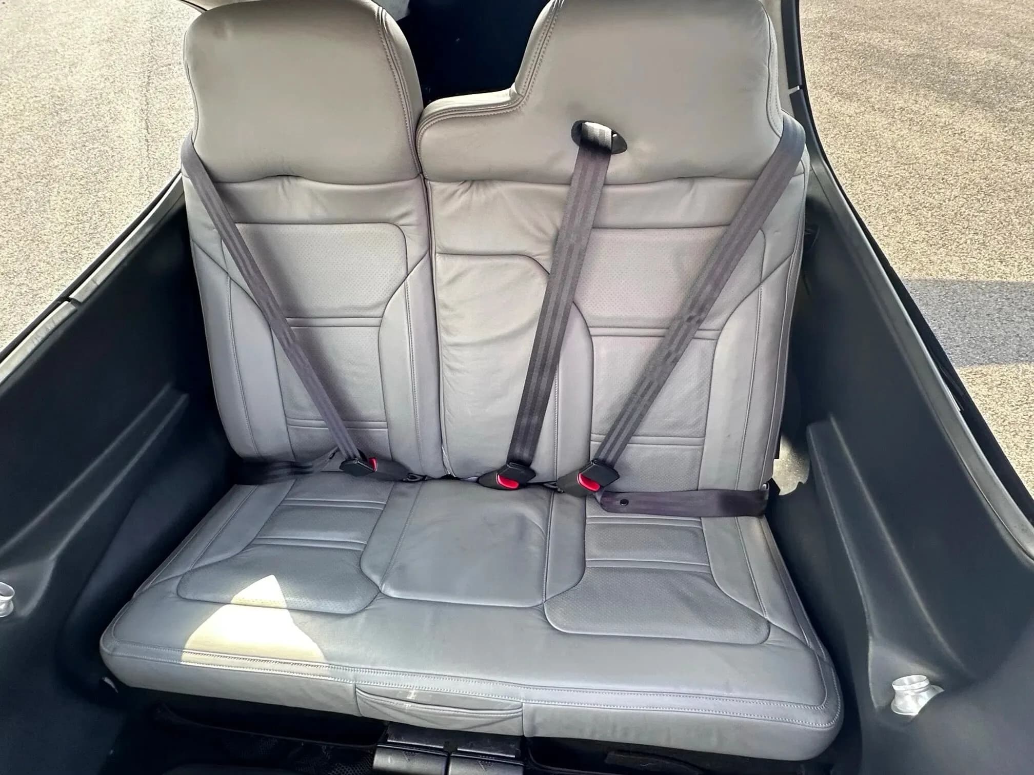 Two grey leather rear passenger seats with harnesses inside the aircraft cabin.
