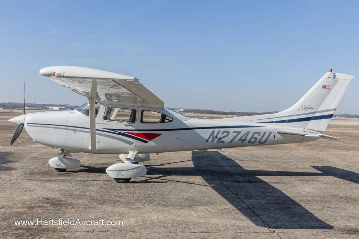 A Cessna Skylane aircraft with a white and gray paint scheme parked on the tarmac.