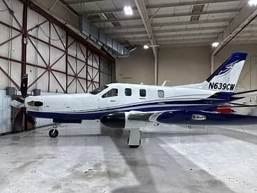 Side view of a white and blue aircraft in a hangar.