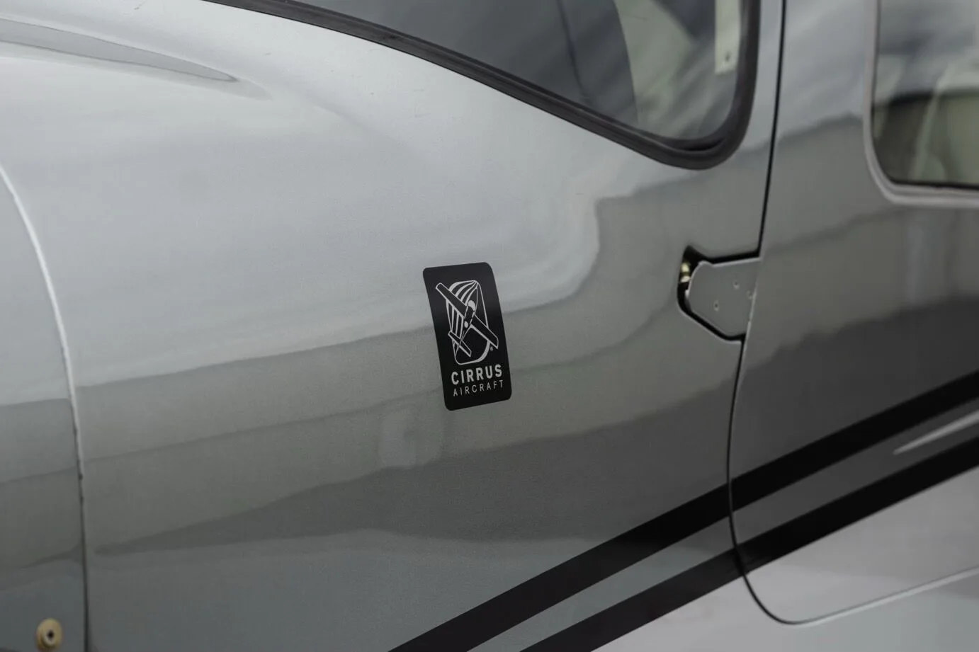 A close-up view of the Cirrus Aircraft logo on the fuselage of the silver Cirrus SR22 GTS Platinum aircraft.