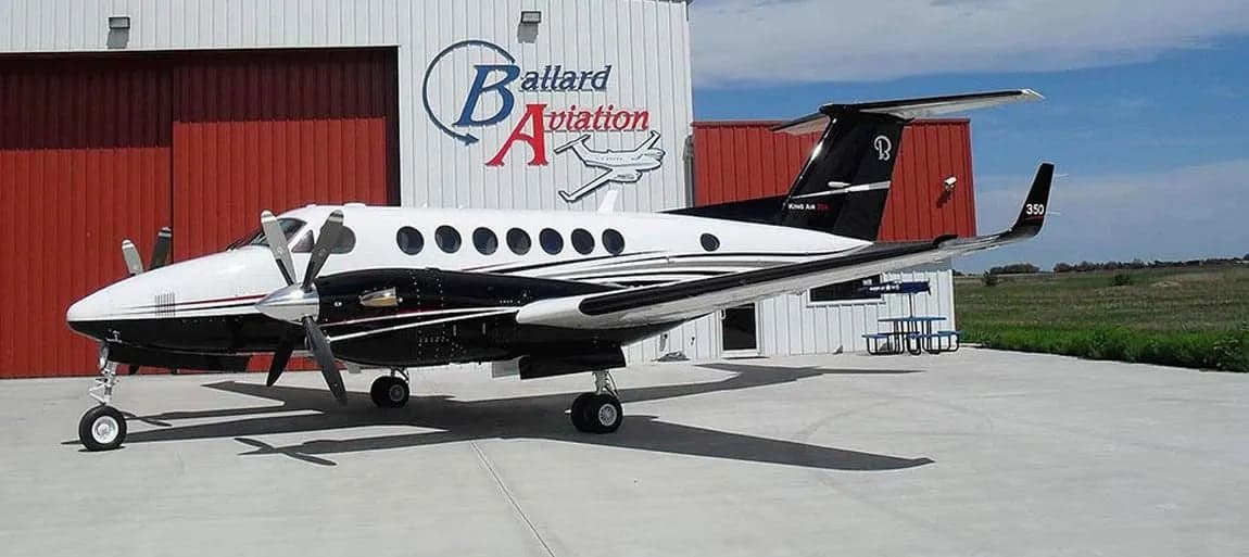 A King Air 350 parked in front of a hangar with the Ballard Aviation logo.