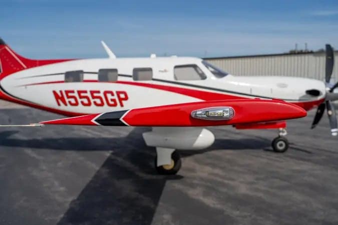 A close-up side view of the white and red Piper M-class aircraft N555GP, highlighting the wingtip and registration.