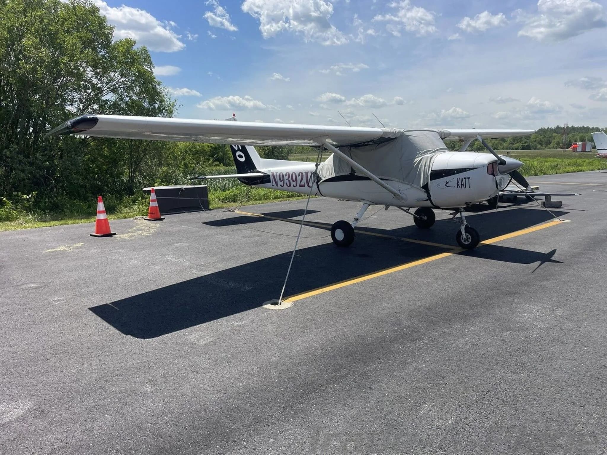 A white single-engine propeller aircraft, N9392U, with a cockpit cover, is parked on an asphalt tarmac.