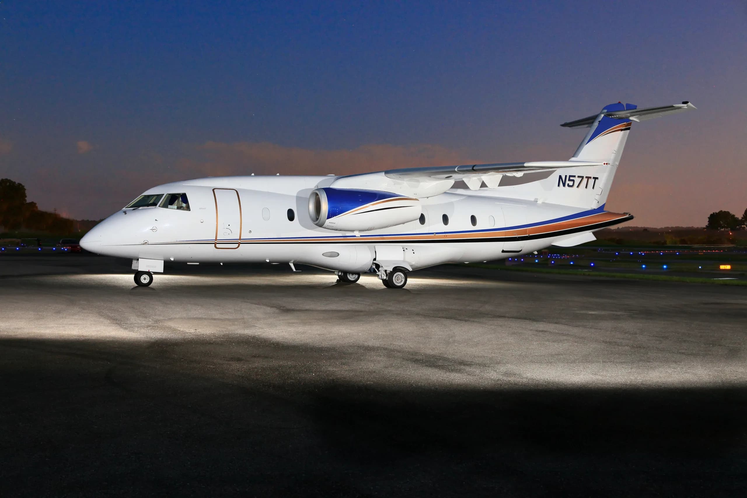 Side view of the N57TT aircraft on the tarmac at dusk.