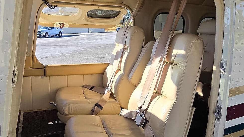 The interior of the aircraft features cream-colored leather seats with seatbelts.