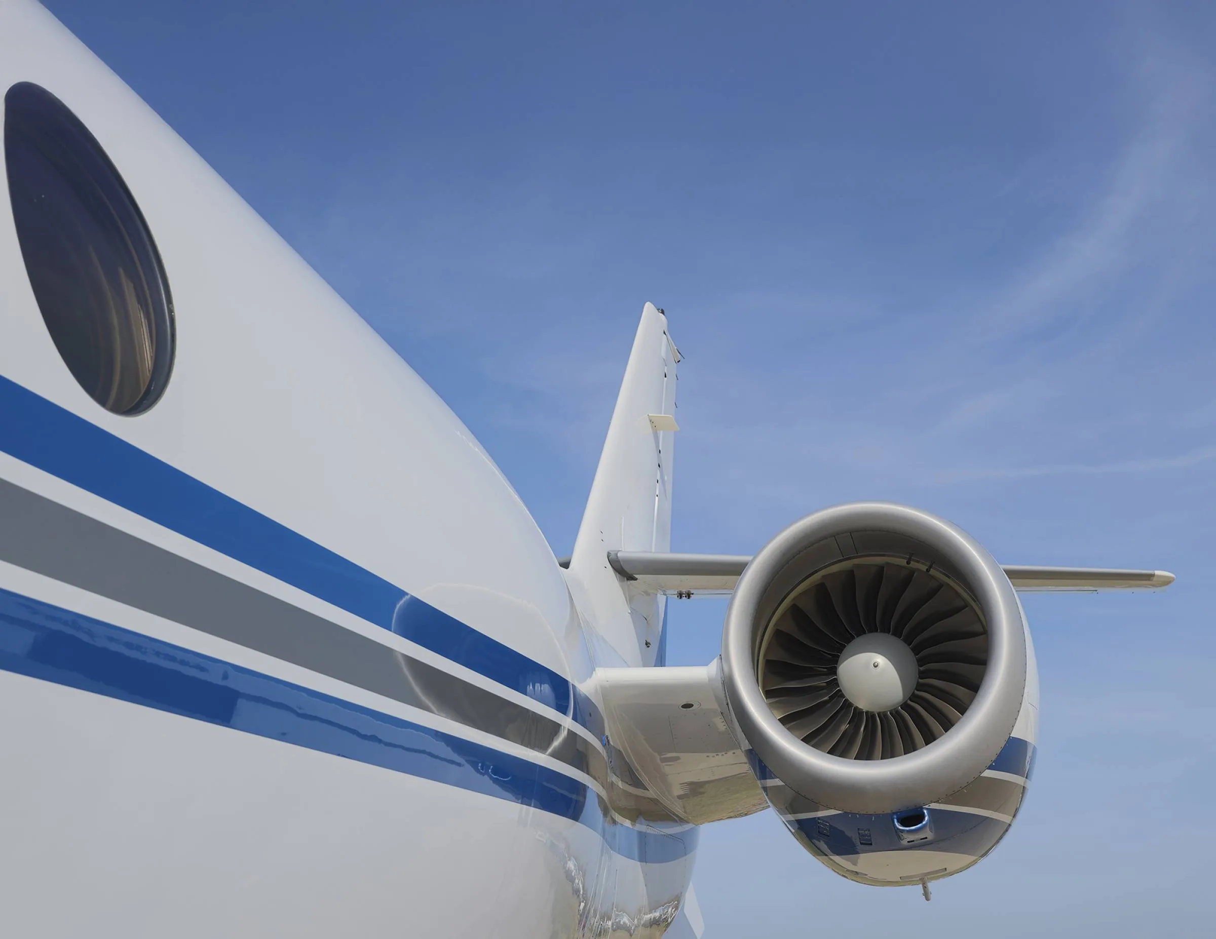 Close up of the tail and engine of a white and blue Gulfstream jet.