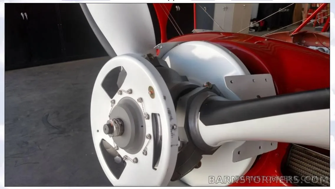 A close-up view of the white propeller and spinner of the red biplane.