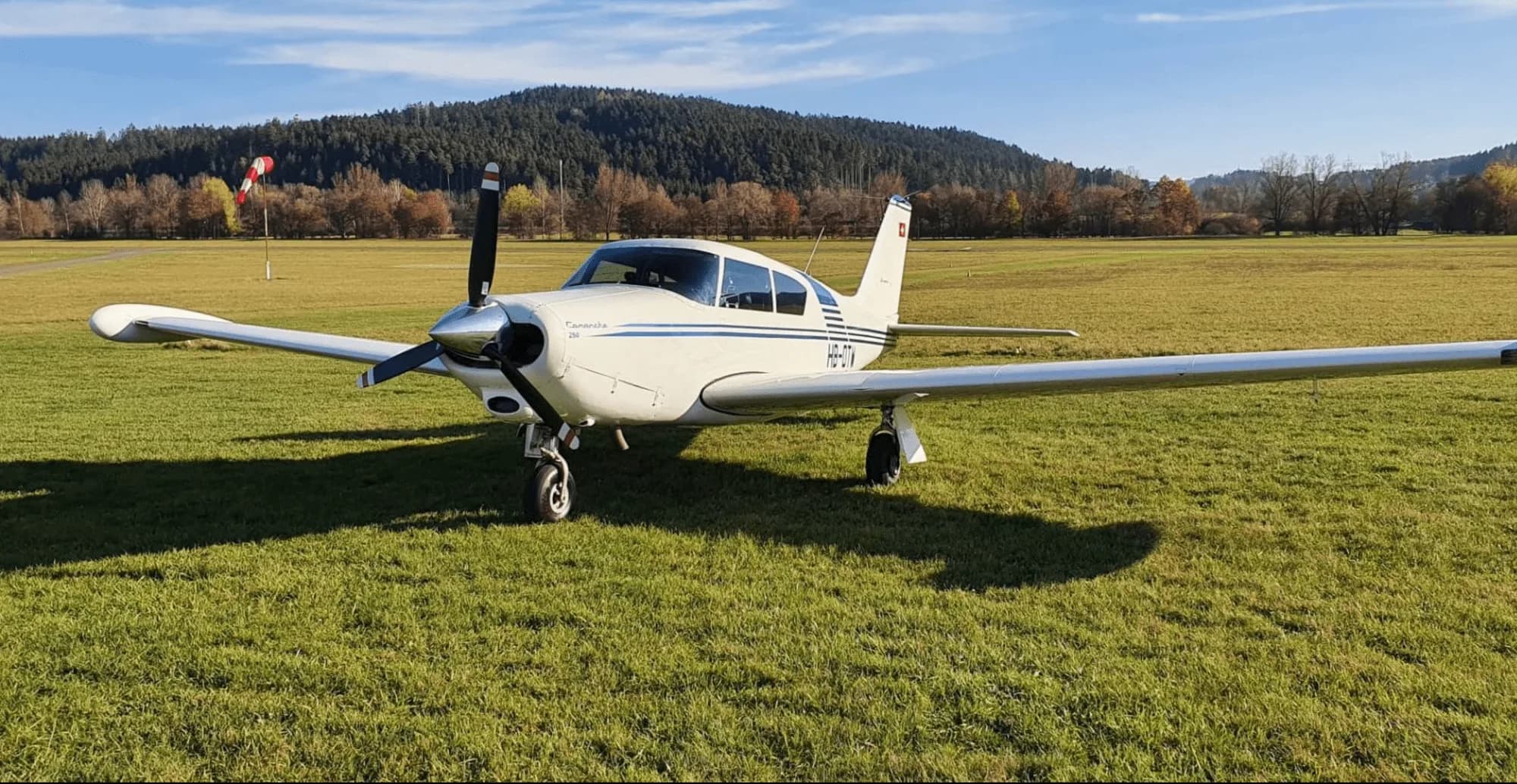 A Piper Comanche 250 parked on a grassy field.