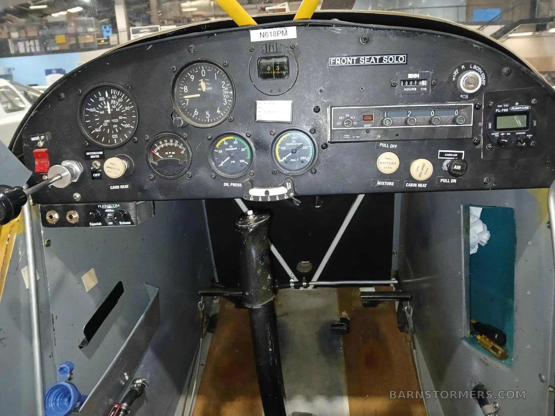 The black instrument panel of a yellow aircraft, showing gauges, radios, and controls.