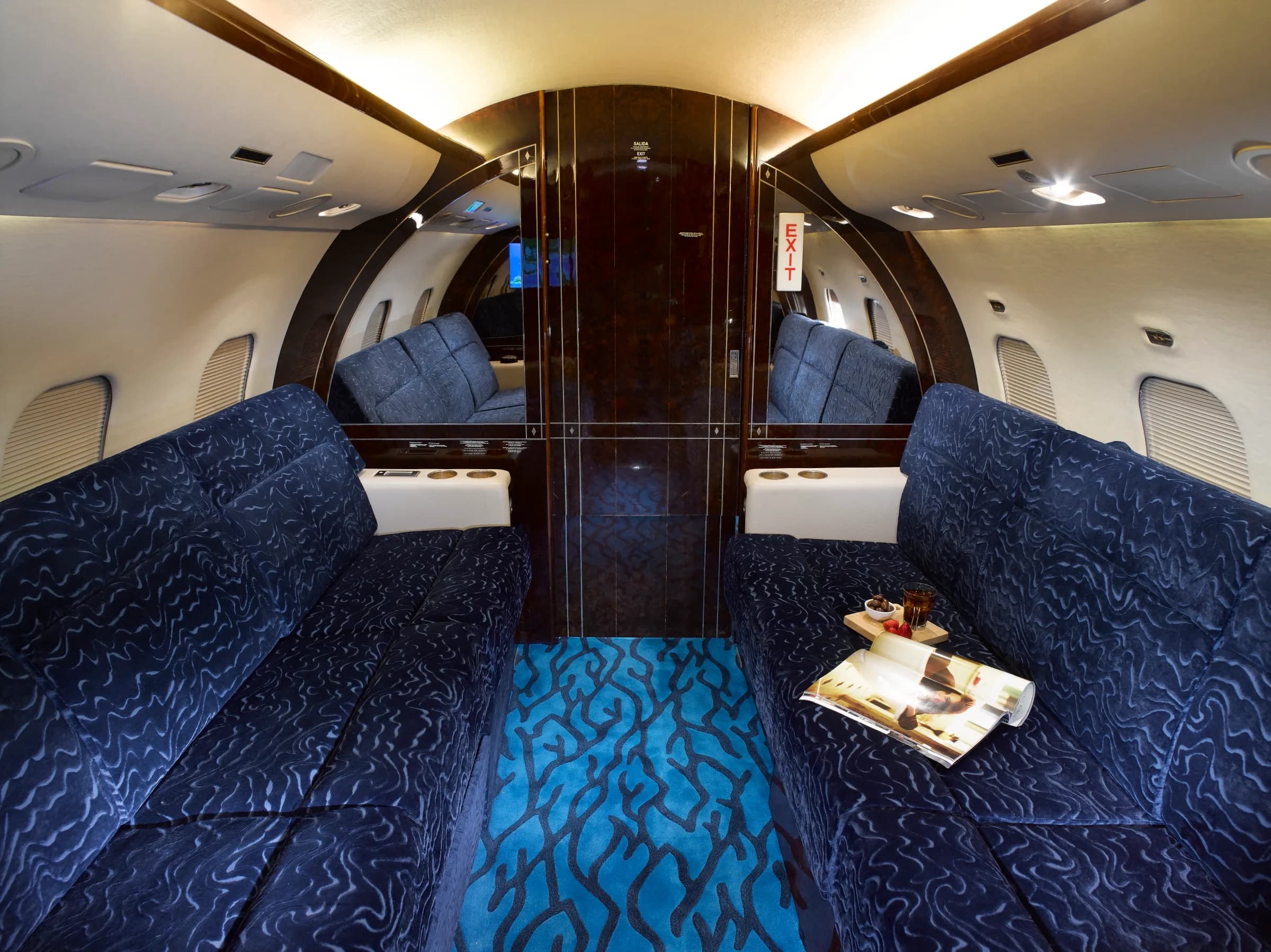 Aft cabin of the aircraft with blue fabric seats and wood accents.
