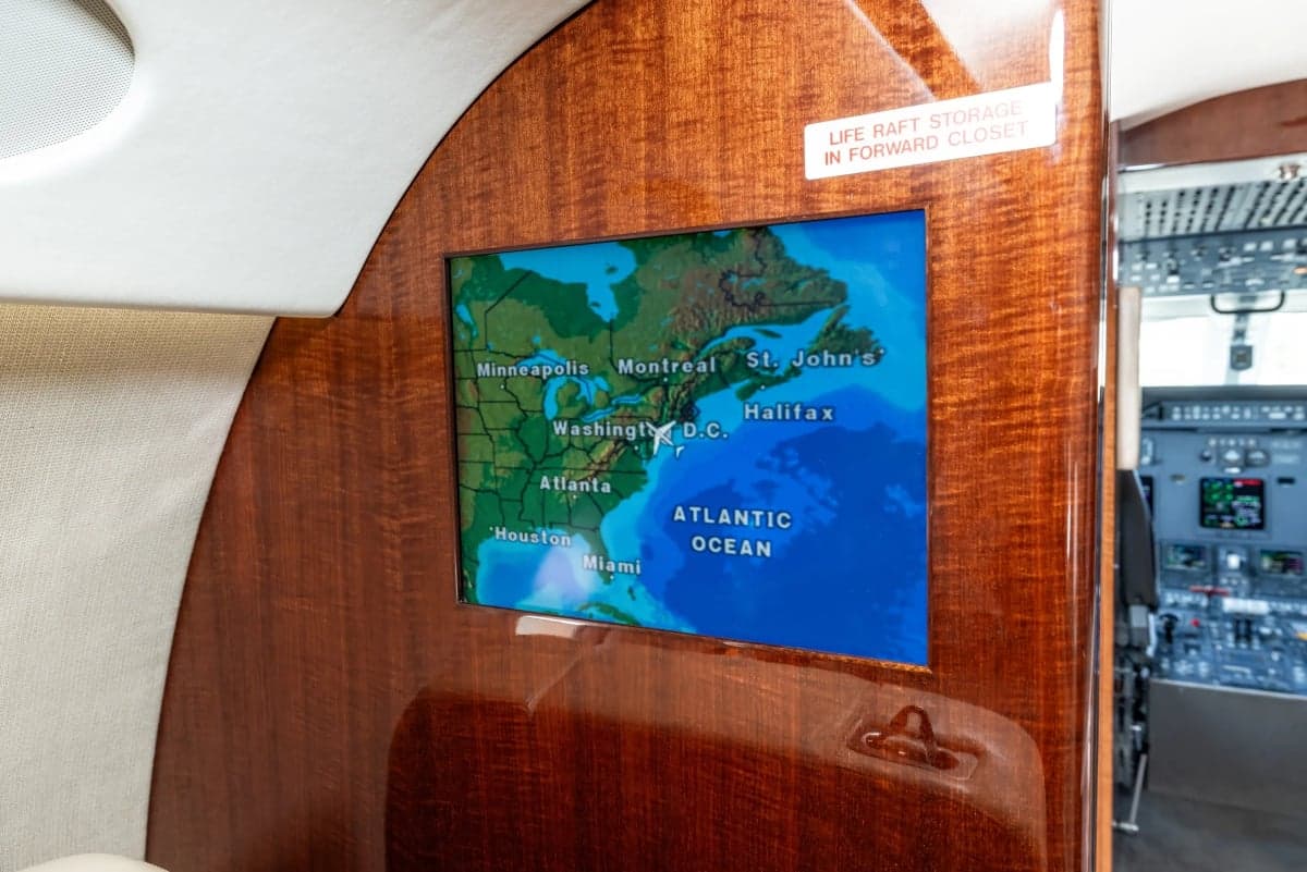 A map of North America is displayed on a screen inside the aircraft cabin.