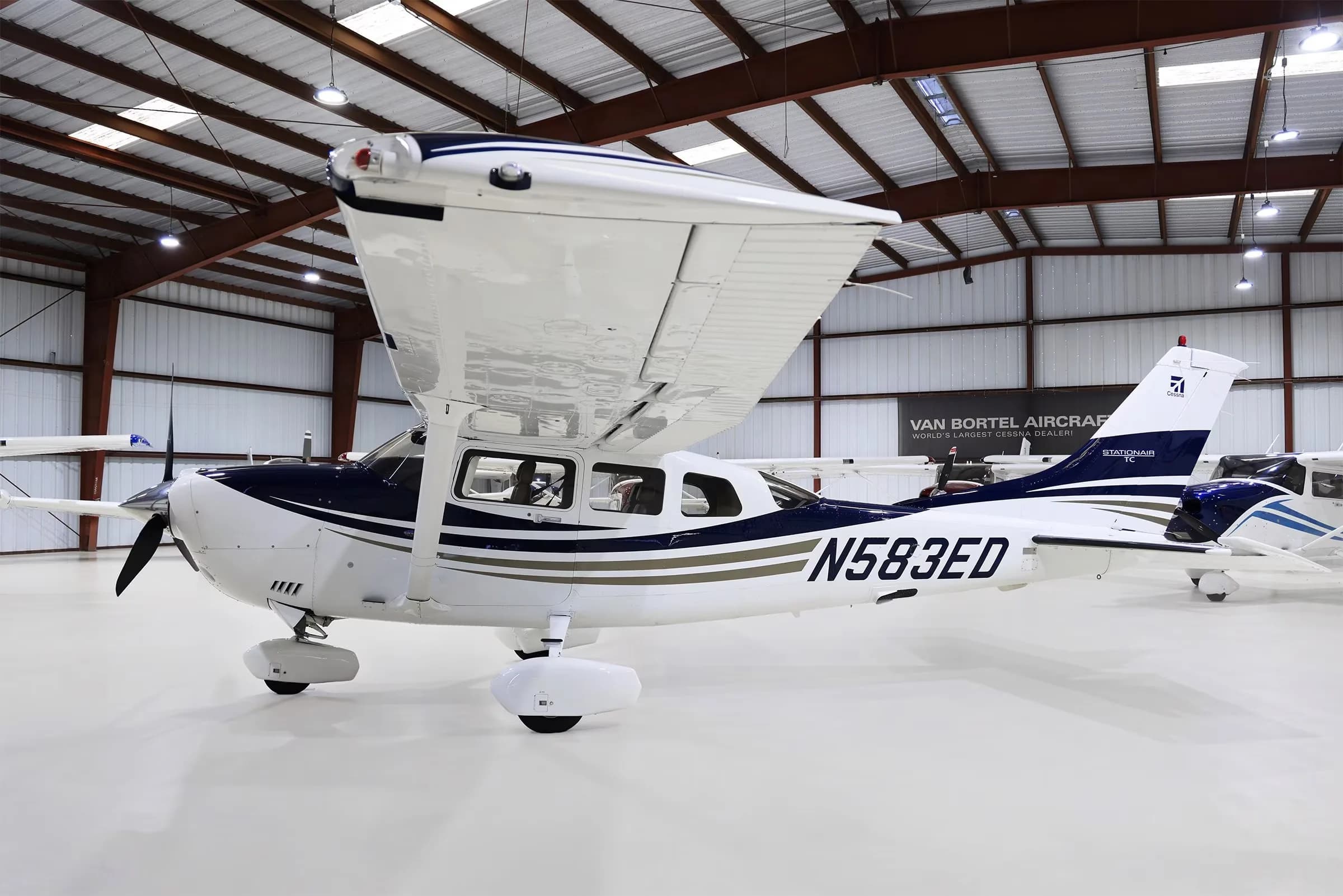 A white and blue Cessna 206 Stationair TC aircraft with tail number N583ED parked in a hangar.